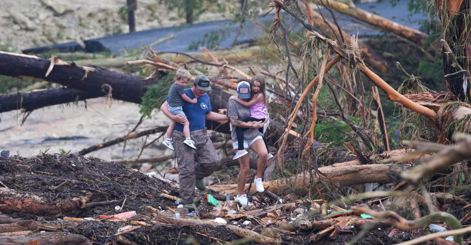  People climb over debris on a bridge near Ingram, Texas