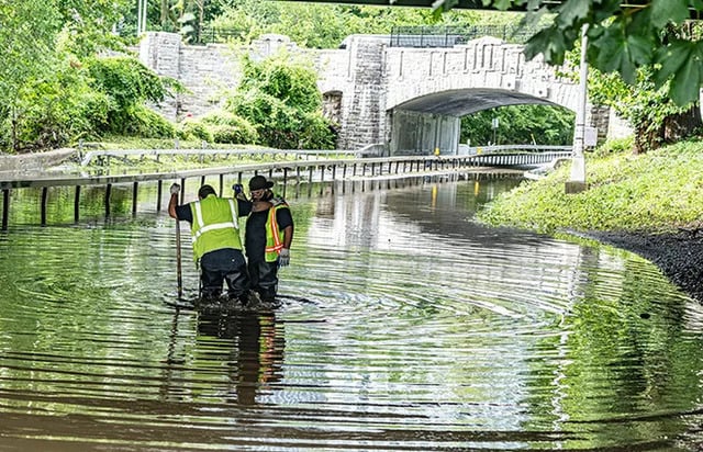 Workers clear clogged drains on the flooded parkway